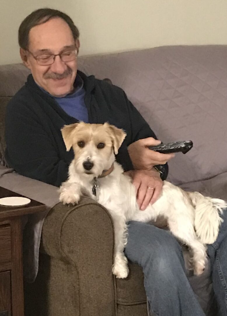 A man sitting on the couch with his dog